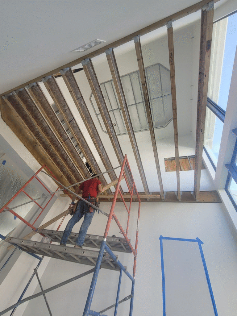 A worker is on a scaffolding inside a house