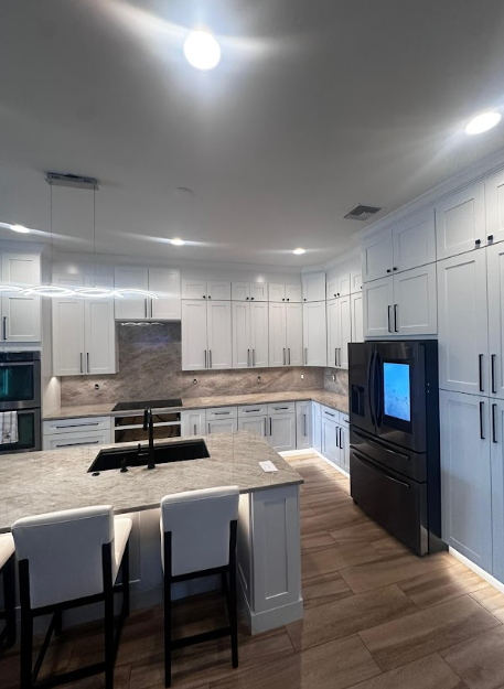 A kitchen with cabinets, appliances, and chairs 